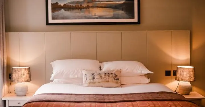Cosy bedroom with a double bed, warm bedside lamps and framed landscape artwork.