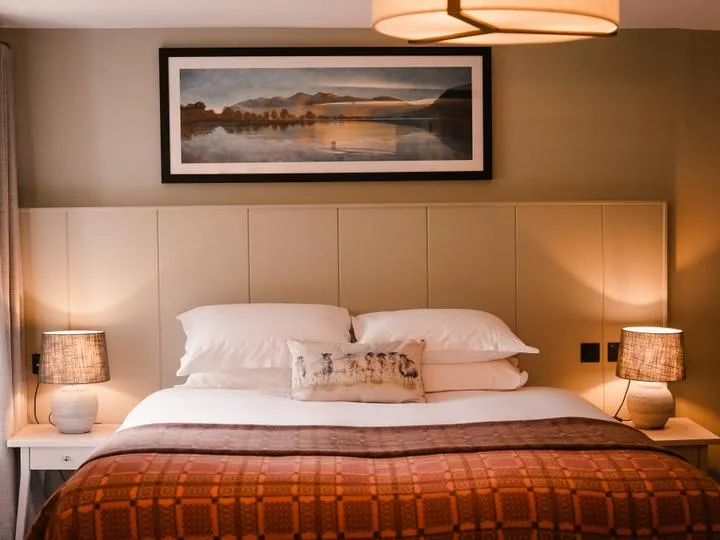 Cosy bedroom with a double bed, warm bedside lamps and framed landscape artwork.