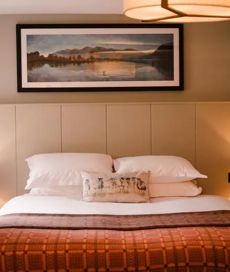 Cosy bedroom with a double bed, warm bedside lamps and framed landscape artwork.