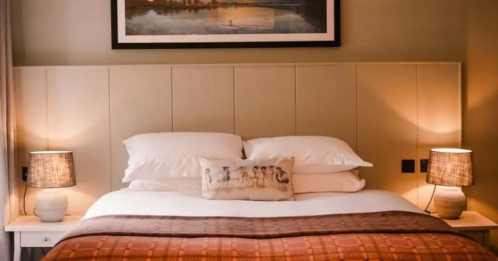 Cosy bedroom with a double bed, warm bedside lamps and framed landscape artwork.
