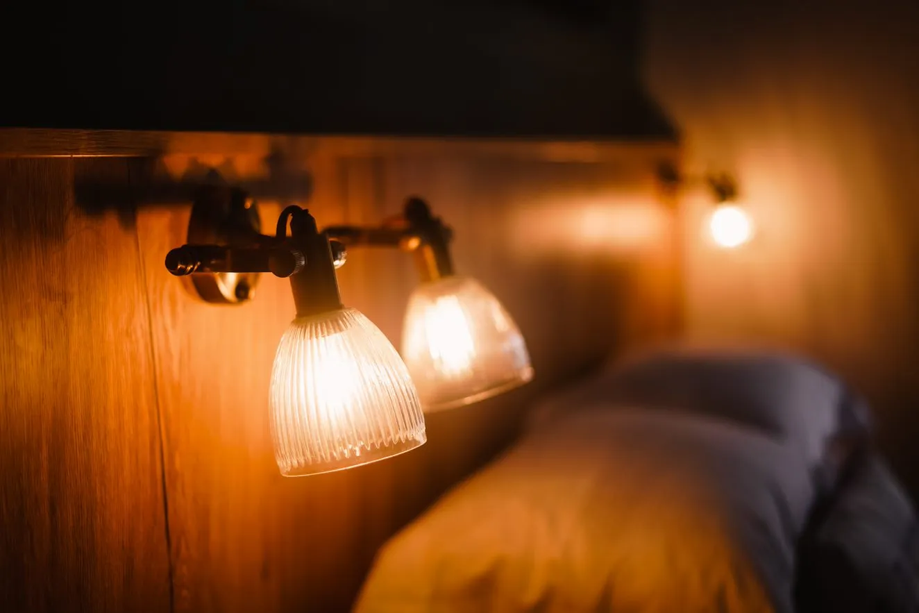 Warm bedside reading lamps with ribbed glass shades above a neatly made bed