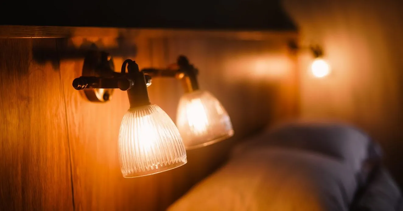 Warm bedside reading lamps with ribbed glass shades above a neatly made bed
