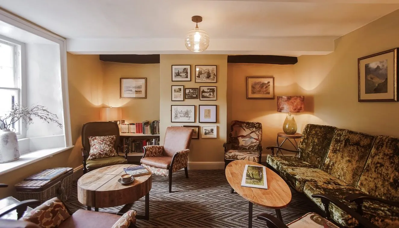 Warm vintage-style sitting room with patterned armchairs, velvet sofa, wooden coffee tables and framed artwork.