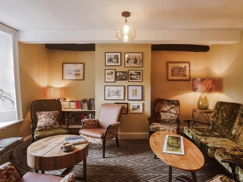 Warm vintage-style sitting room with patterned armchairs, velvet sofa, wooden coffee tables and framed artwork.