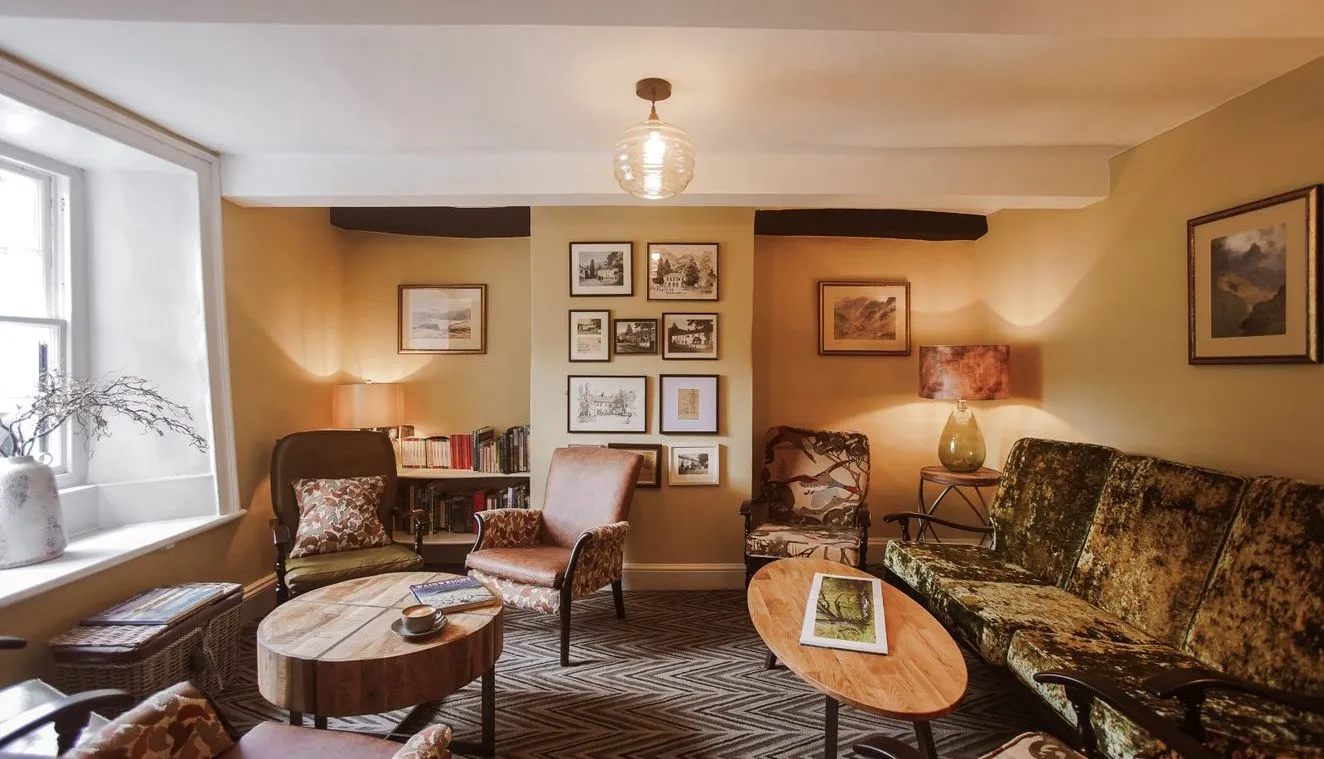 Warm vintage-style sitting room with patterned armchairs, velvet sofa, wooden coffee tables and framed artwork.