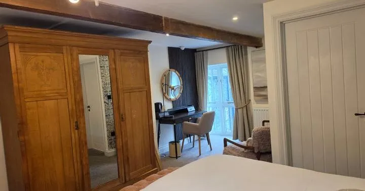 Cosy bedroom with wooden wardrobe, exposed beams and a desk by French doors