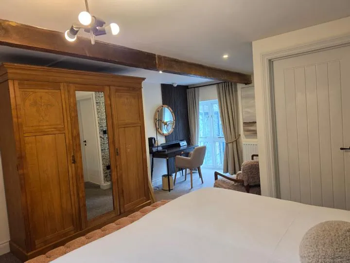 Cosy bedroom with wooden wardrobe, exposed beams and a desk by French doors