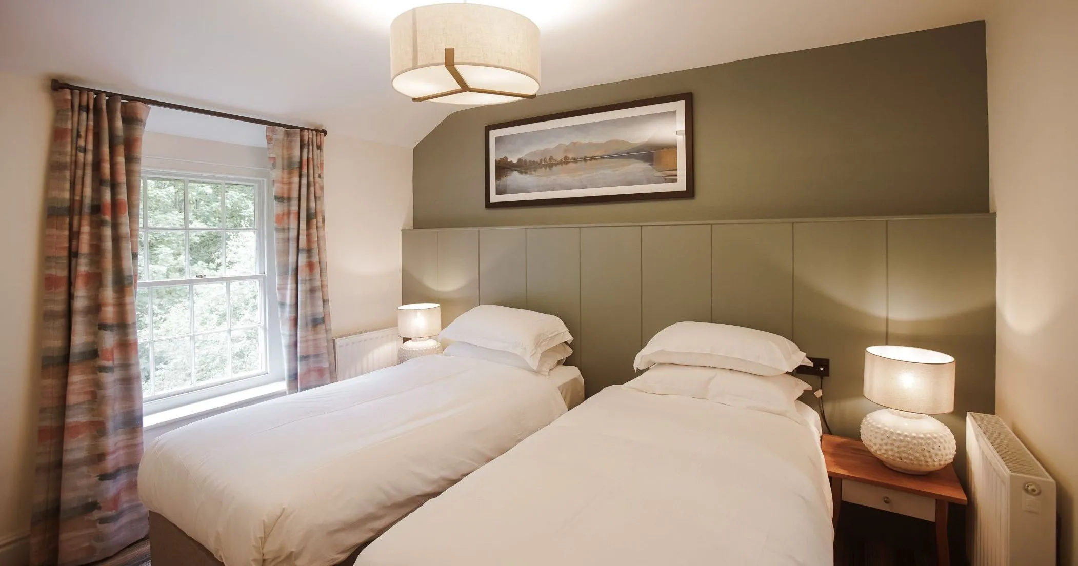 Cosy twin bedroom with two single beds, bedside lamps and patterned curtains