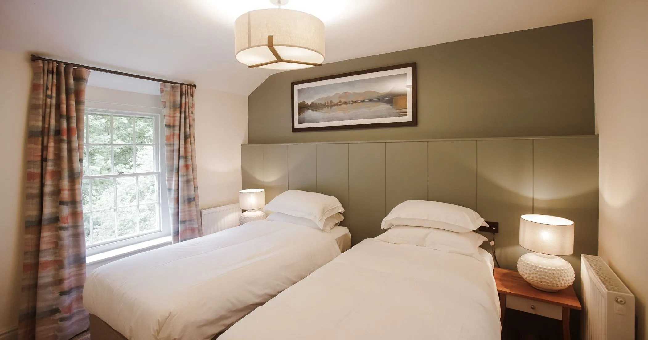 Cosy twin bedroom with two single beds, bedside lamps and patterned curtains