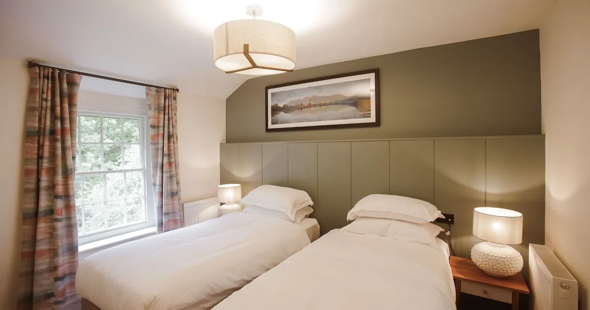 Cosy twin bedroom with two single beds, bedside lamps and patterned curtains