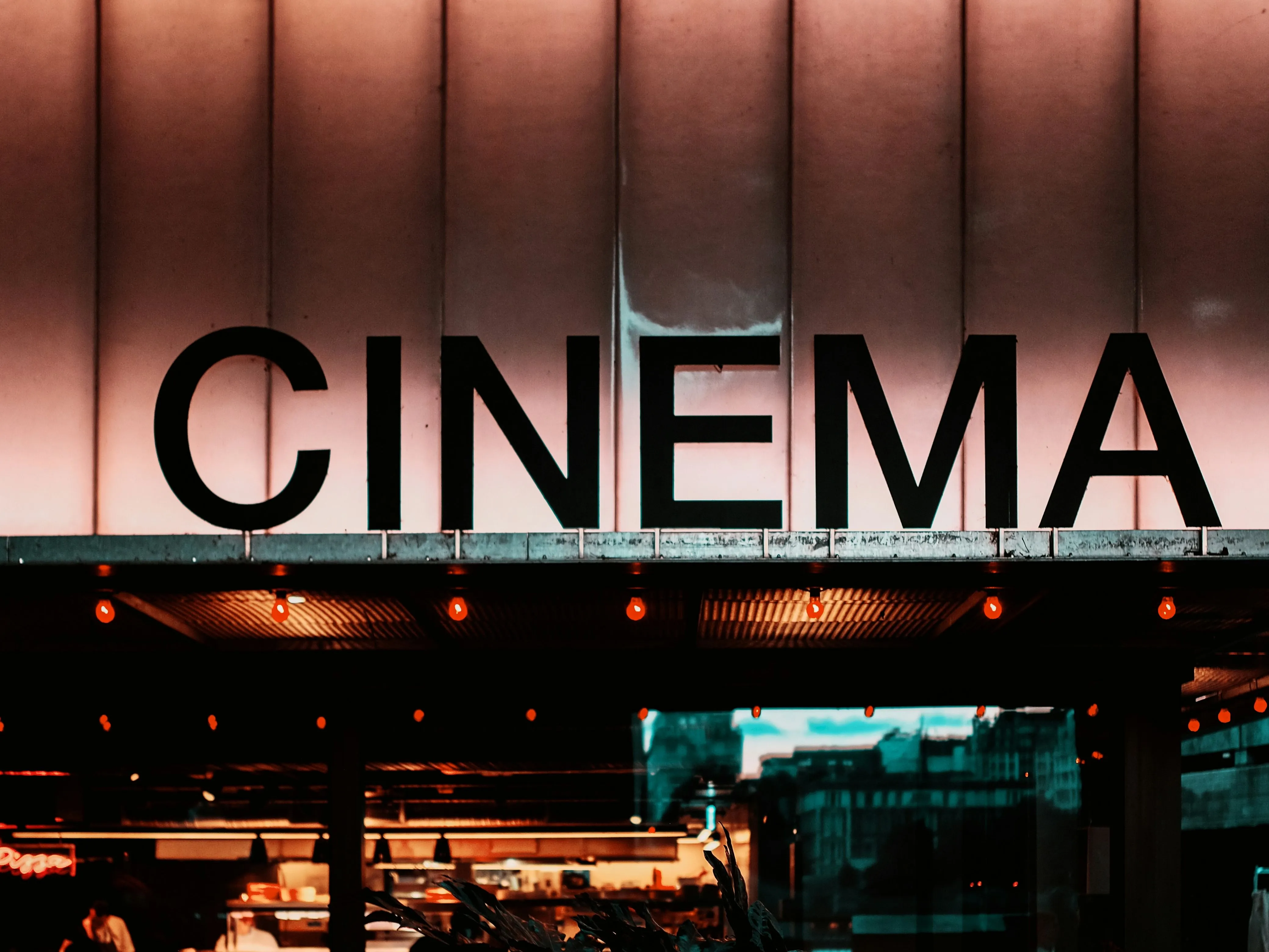Illuminated CINEMA sign above a warmly lit entrance at night
