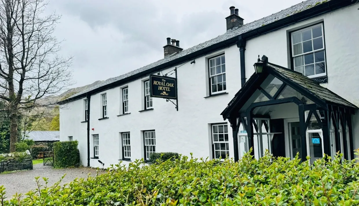 Exterior of The Royal Oak Hotel, a white traditional country inn with a black timber porch and slate roof.