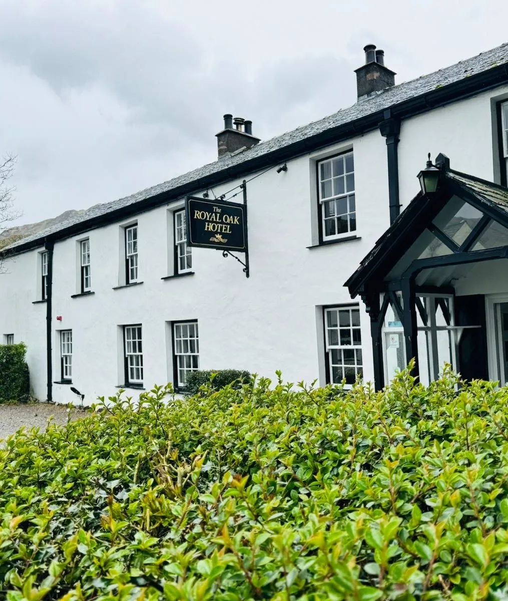 Exterior of The Royal Oak Hotel, a white traditional country inn with a black timber porch and slate roof.