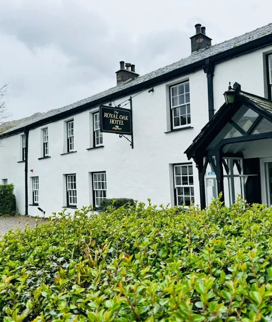 Exterior of The Royal Oak Hotel, a white traditional country inn with a black timber porch and slate roof.