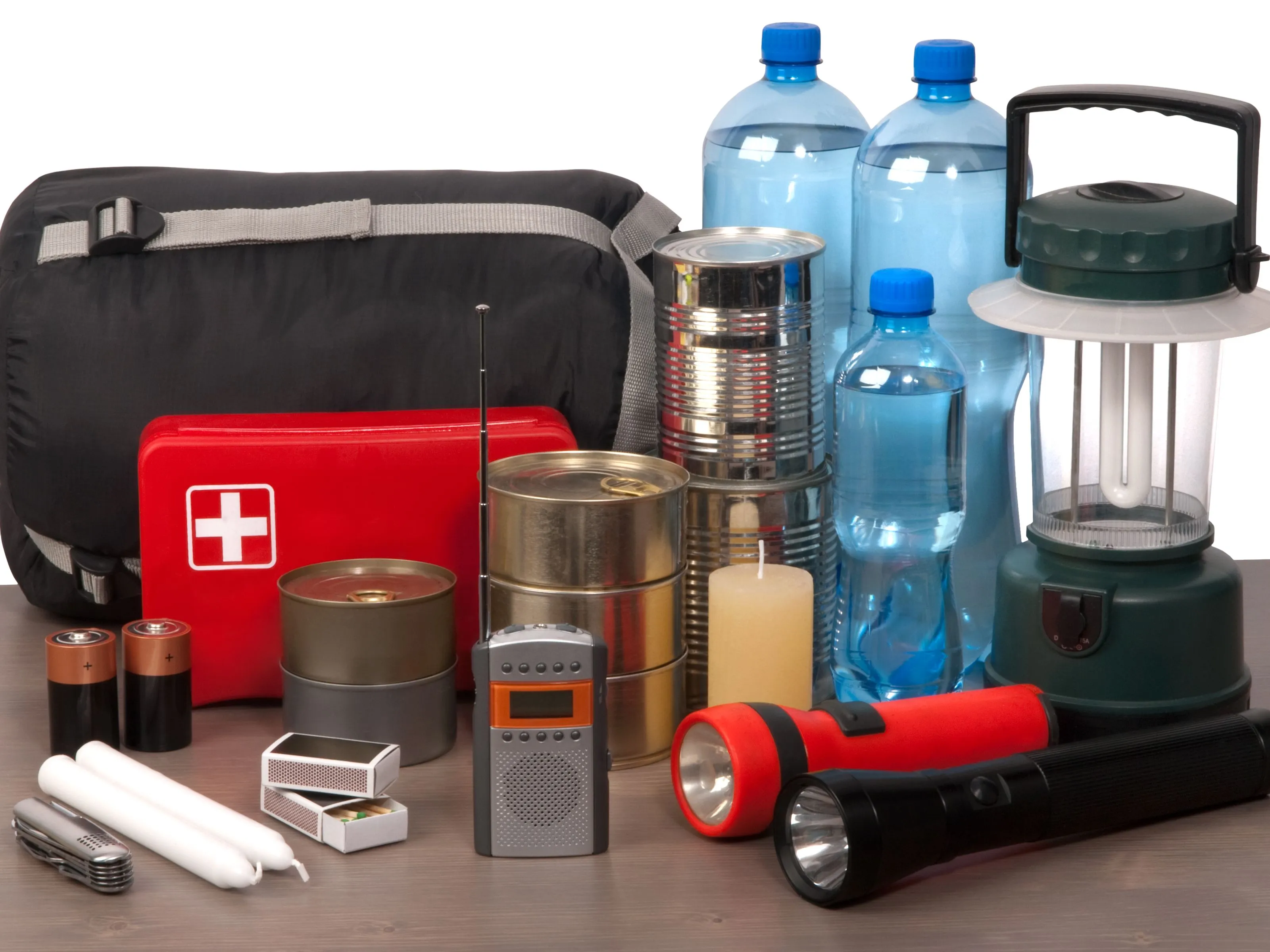 Emergency preparedness supplies including a first aid kit, bottled water, tinned food, torches, candles and a camping lantern.