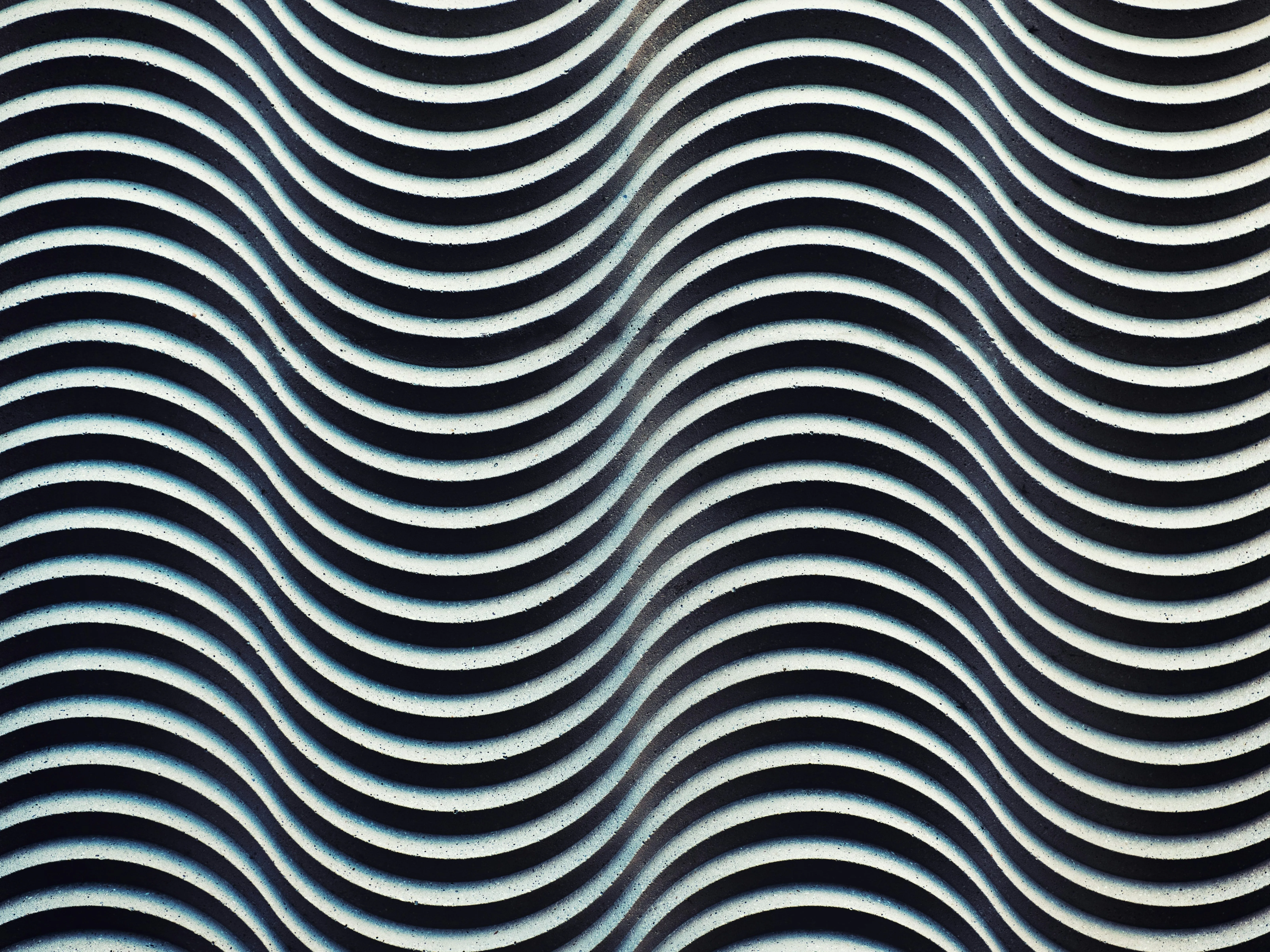 Abstract black and white wavy striped pattern with a textured surface.