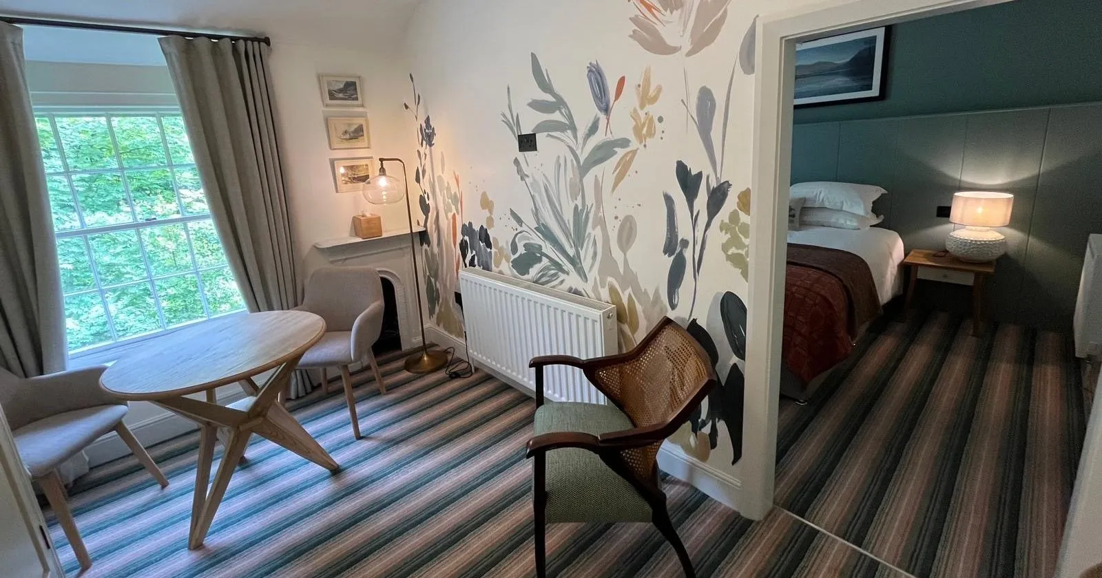 Cosy dining area with a round table, floral mural wall and adjoining bedroom.