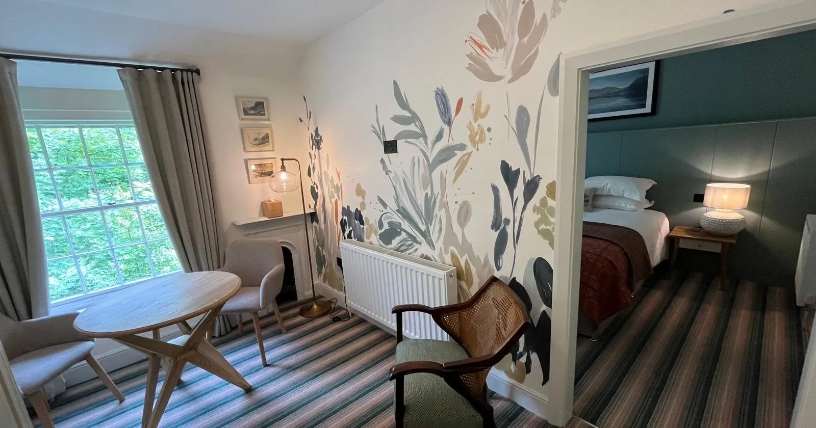 Cosy dining area with a round table, floral mural wall and adjoining bedroom.