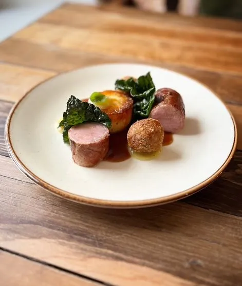 Gourmet plate of sliced pork sausage with roasted potato, kale and croquette