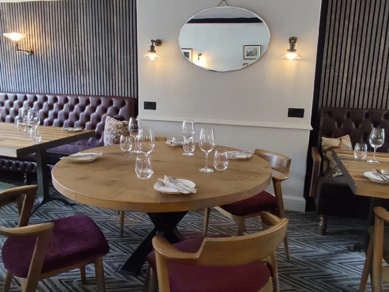 Stylish restaurant dining area with wooden tables, upholstered booth seating and place settings.