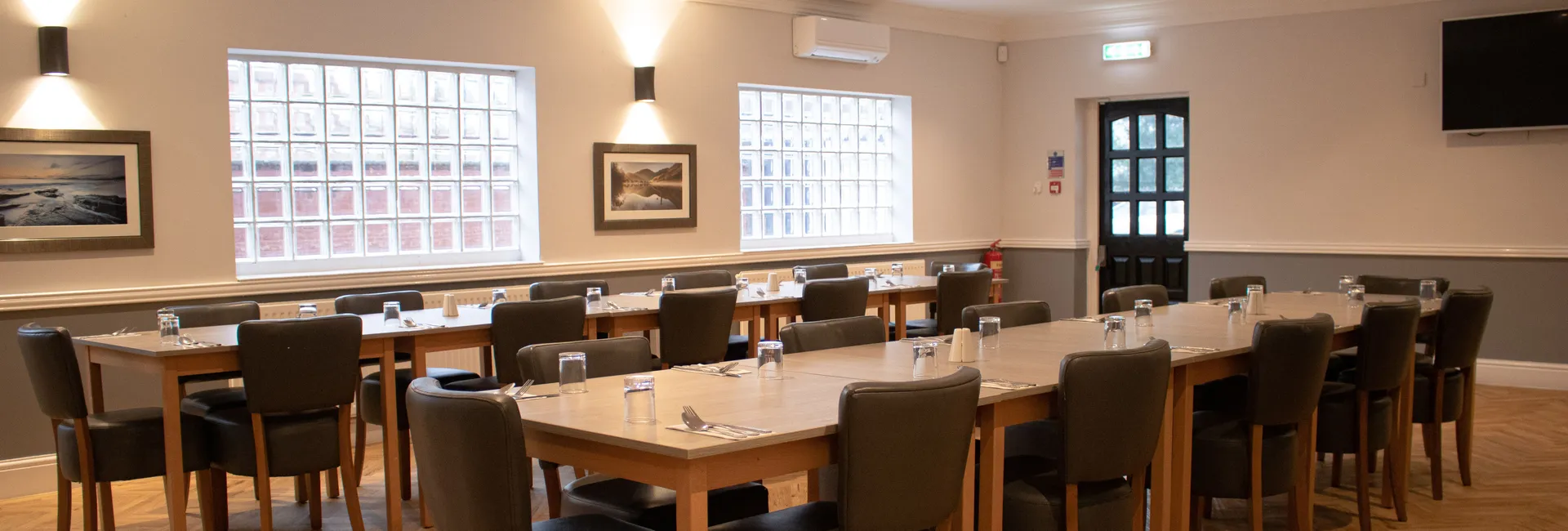 Spacious event room with modern decor, set up with tables and chairs for a meeting or dining event.