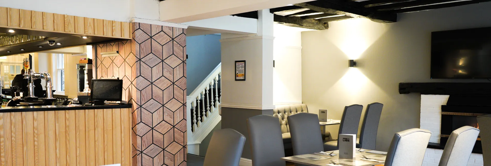 Modern restaurant interior with grey chairs, wood flooring, and a bar area