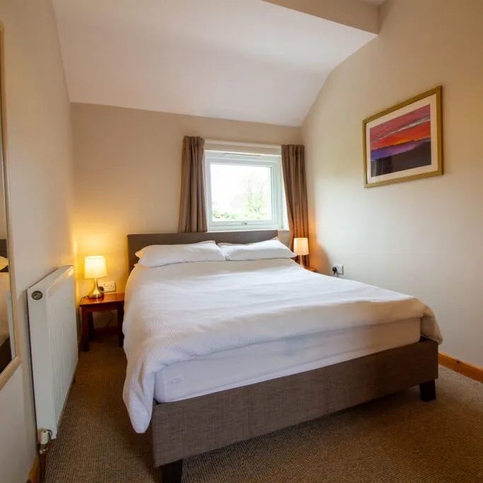 Cozy bedroom with a double bed, lamps, and a window