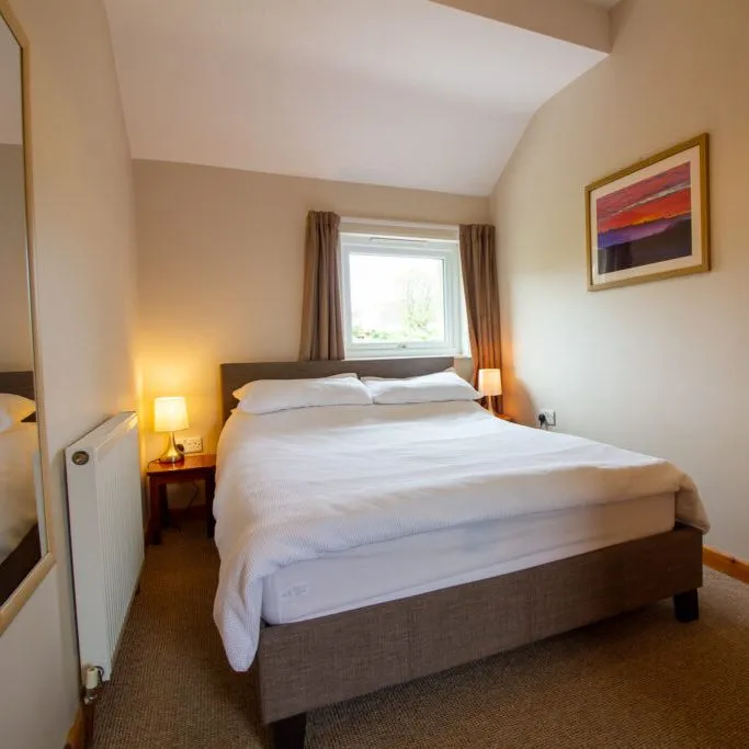 Cozy bedroom with a double bed, lamps, and a window