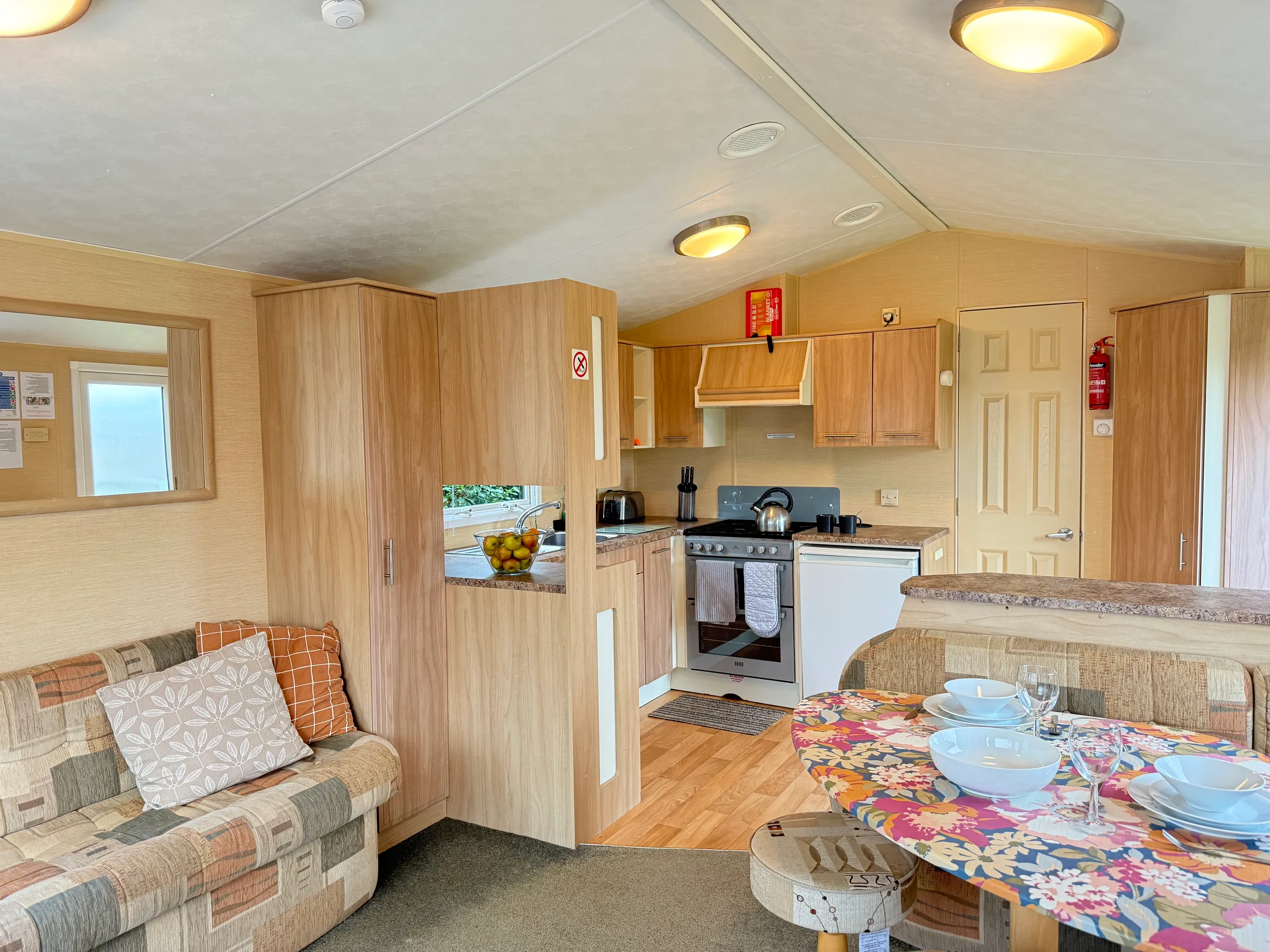 Interior of a cozy mobile home with kitchen, sofa, and dining area