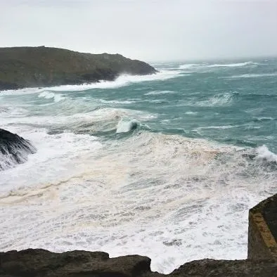 View of rough ocean waves and rocky coastline seen through an old stone window frame