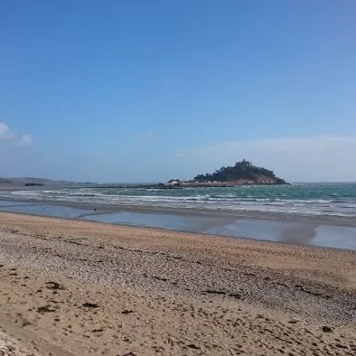 View of St Michael's Mount from a sandy beach under a clear blue sky
