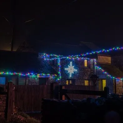 Stone cottage decorated with colorful Christmas lights at night