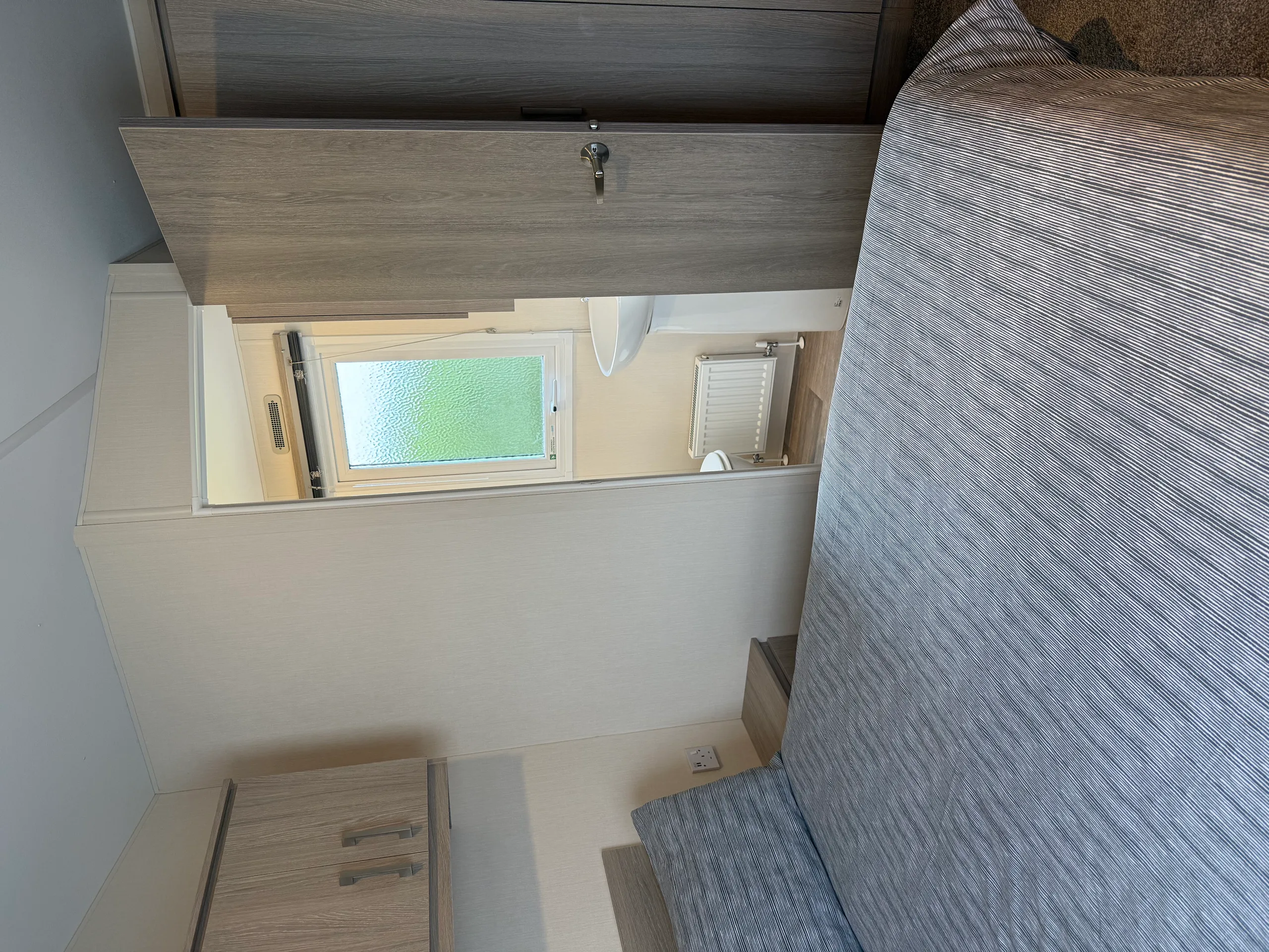 A modern bedroom with a neatly made bed and an open door revealing a small bathroom.