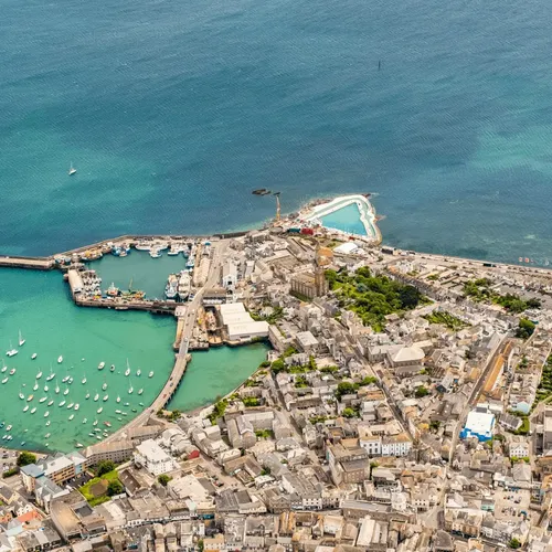 Aerial view of a coastal town with a marina, harbor, and surrounding urban area.