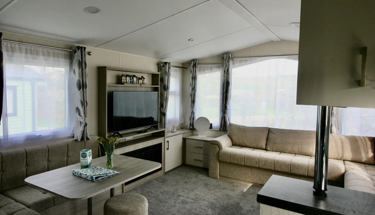 Modern living room with large windows, beige sofas, and flat screen TV
