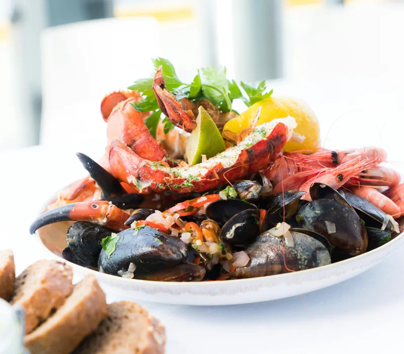 Plate of mixed seafood including lobster, shrimp, mussels, and bread slices