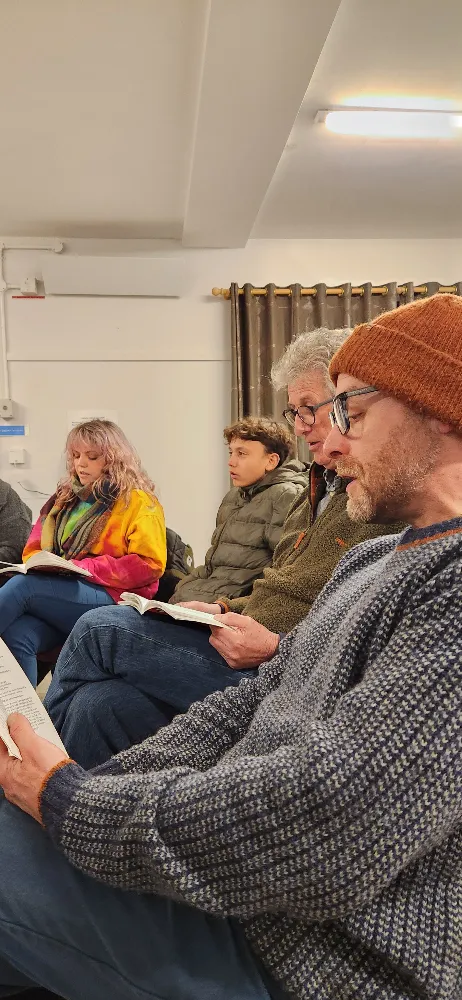 Group of people sitting indoors, each holding and reading from a book.