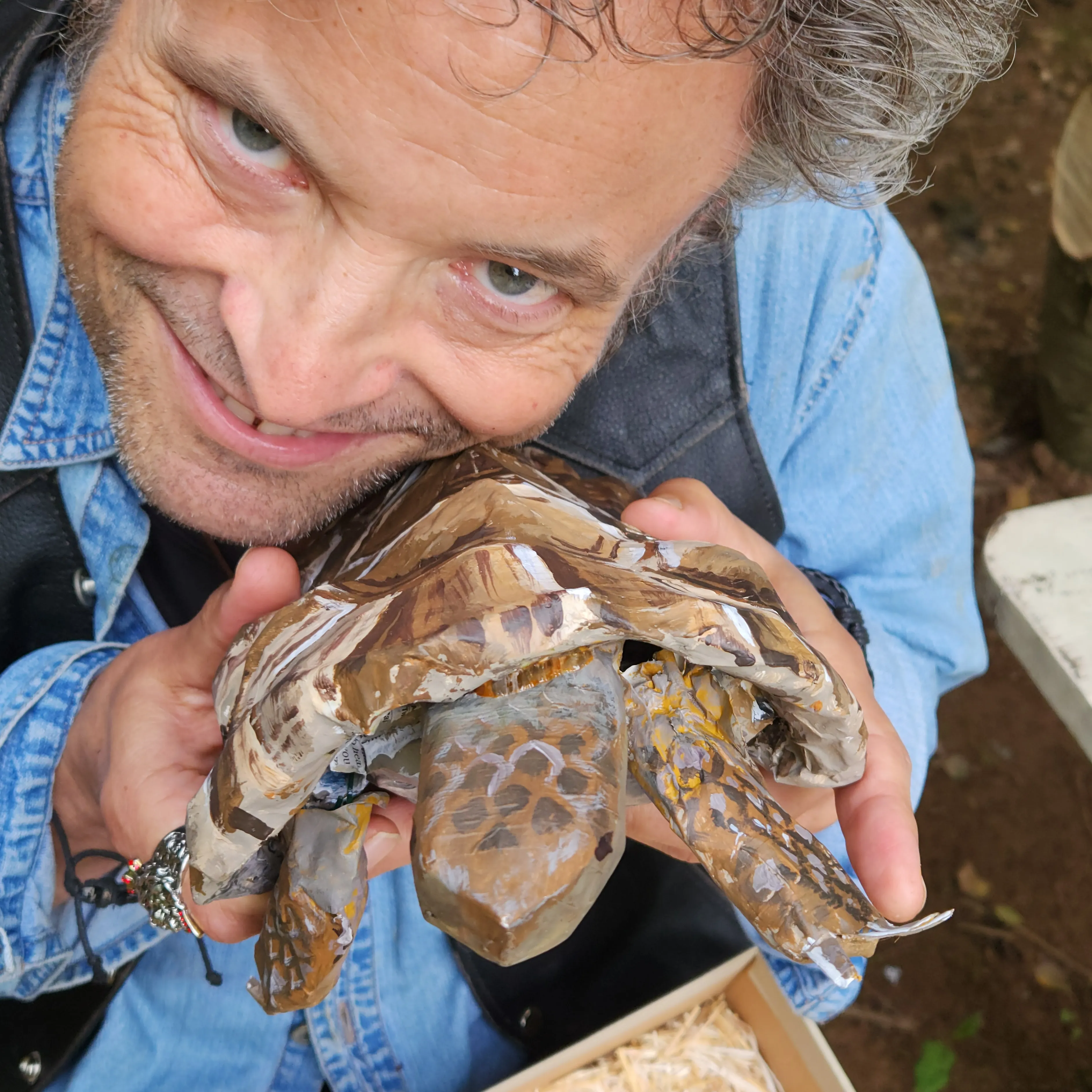 Man smiling and holding a realistic looking paper mache turtle