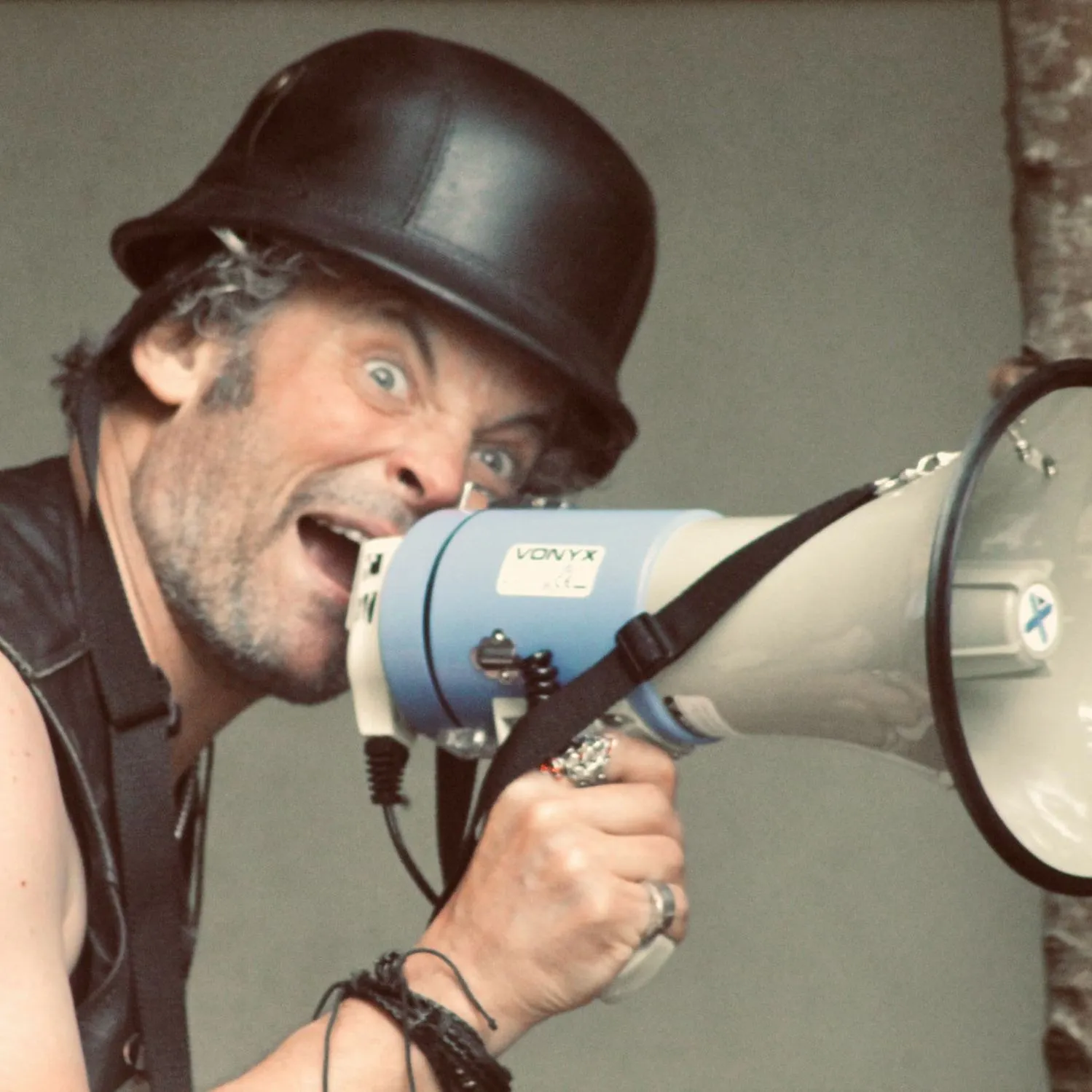 Man with a black helmet shouting into a megaphone