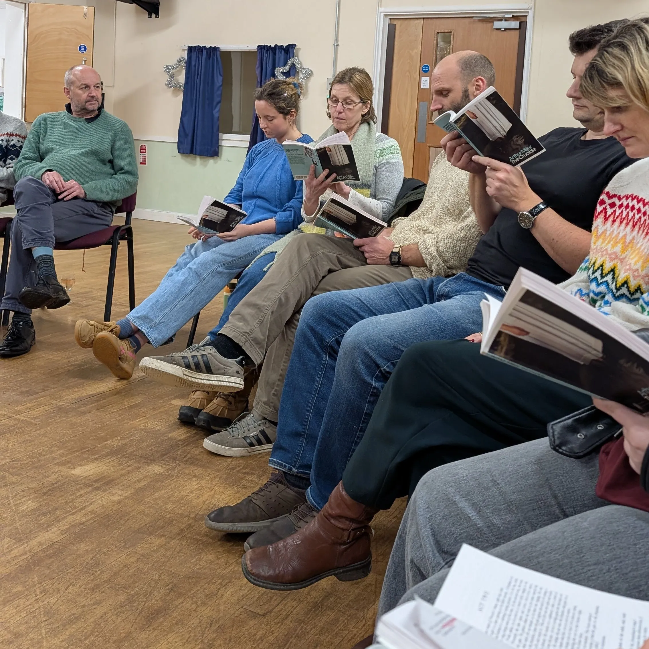 A group of people sitting in a circle reading books in a decorated room.