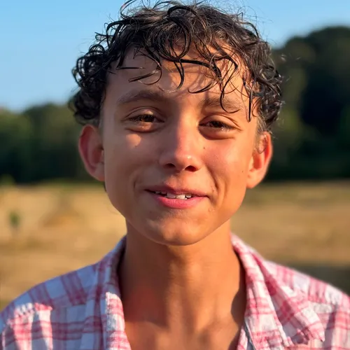 Close-up portrait of Balthasar Freddie Carder outdoors in warm evening light, wearing a pink checked shirt.
