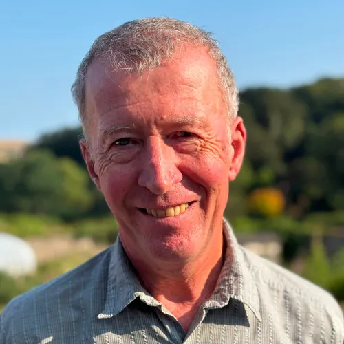 Portrait of Bill Thom smiling outdoors in warm evening light