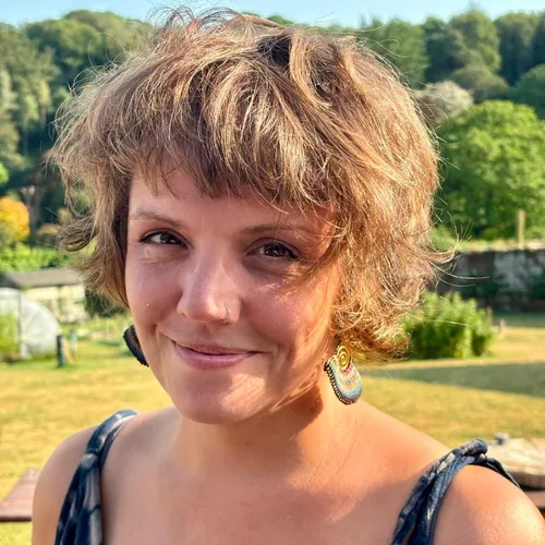 Portrait of Nurse Lucy Barritt smiling outdoors in sunny countryside surroundings.