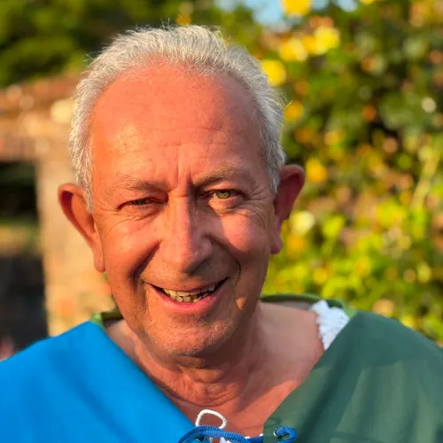 Portrait of Peter Chris Field smiling outdoors in sunlight, wearing a blue and green costume.