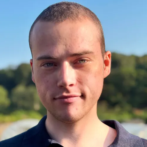 Portrait of Sampson Charlie Papenfus outdoors in natural sunlight, wearing a dark polo shirt