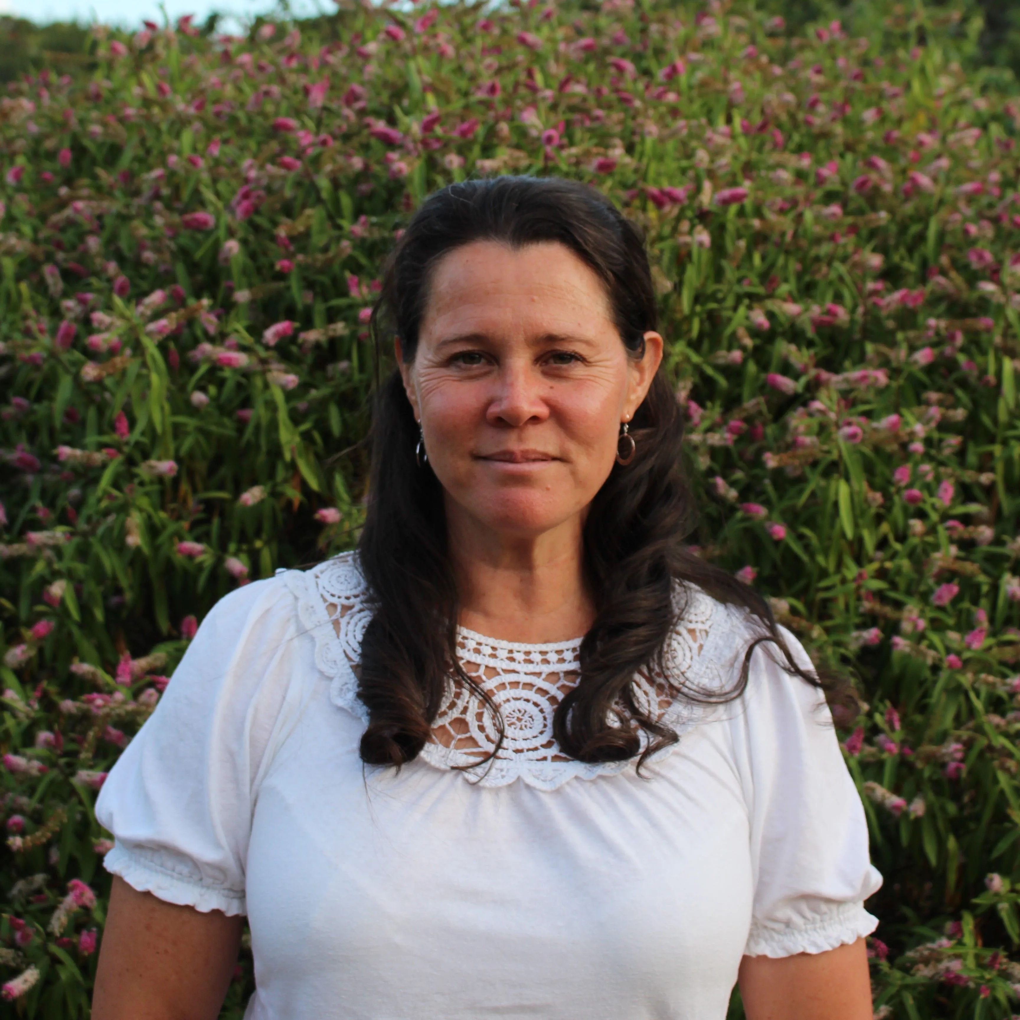 Portrait of Angie standing in front of pink flowering plants