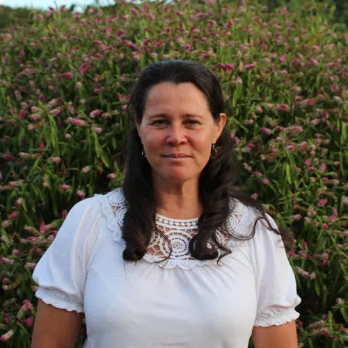 Portrait of Angie standing in front of pink flowering plants