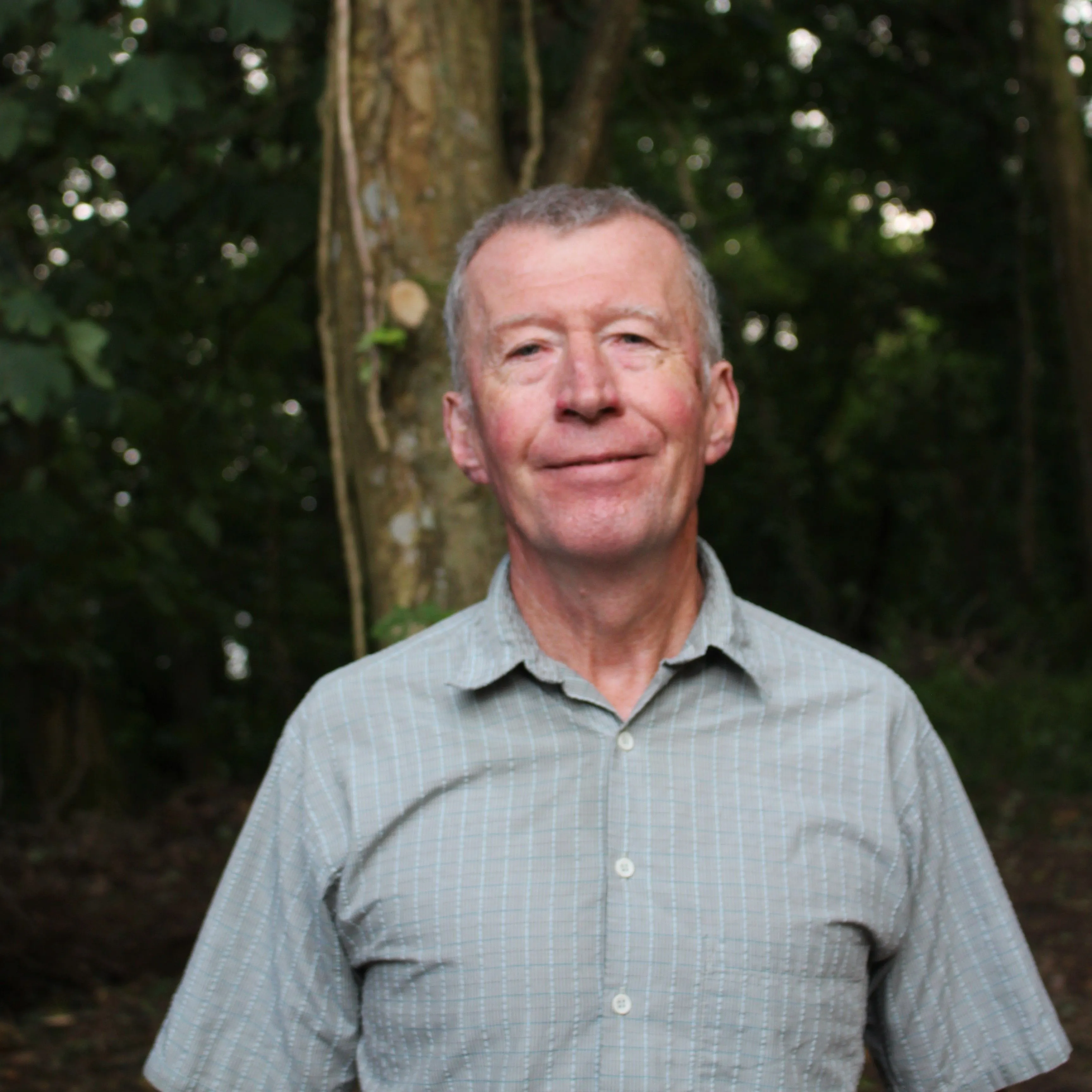Portrait of an older man smiling outdoors in a wooded area