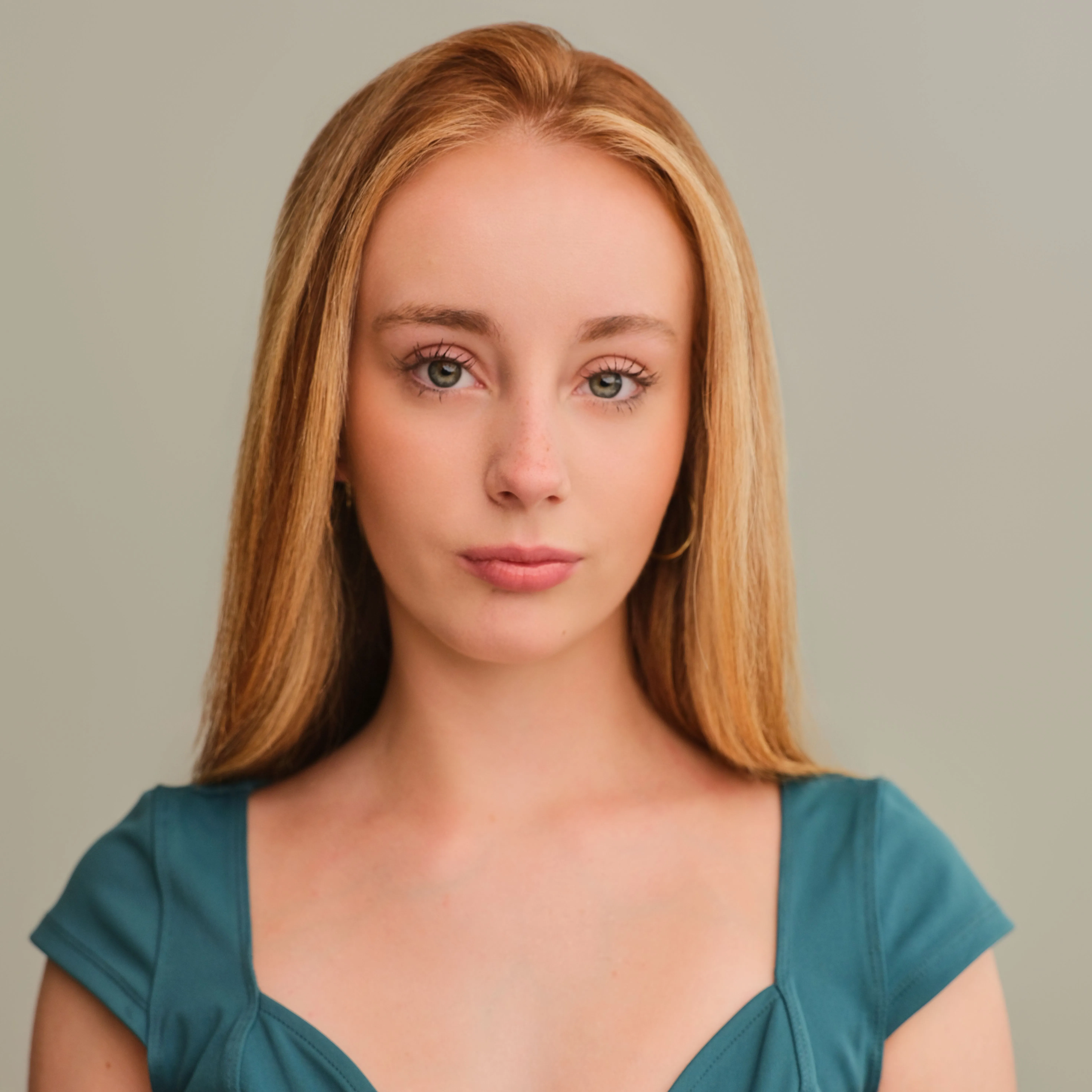 Studio portrait of a woman with long blonde hair wearing a teal dress