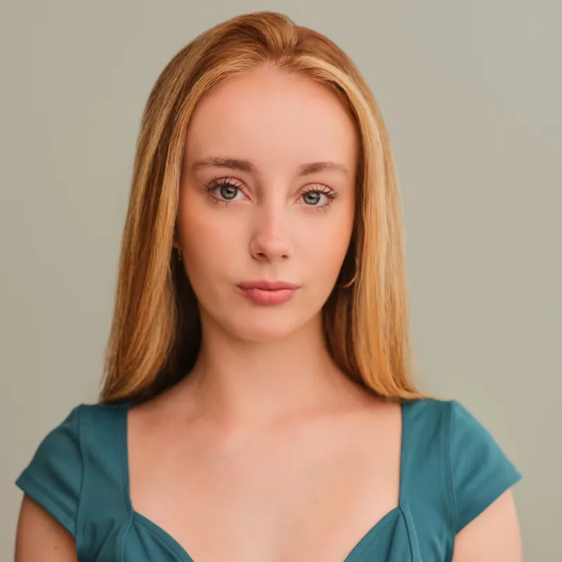 Studio portrait of a woman with long blonde hair wearing a teal dress